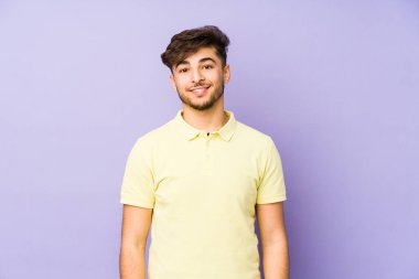 Mor arka planda izole edilmiş genç bir Arap adam mutlu, güler yüzlü ve neşeli..