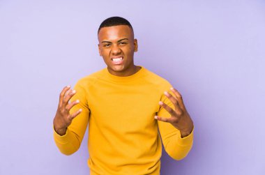 Mor arka planda izole edilmiş genç latin adam gergin ellerle çığlık atıyor..