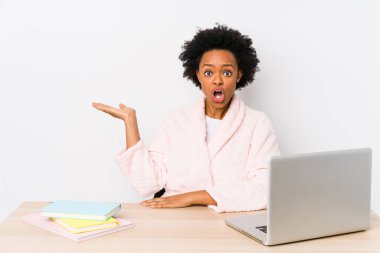 Orta yaşlı Afro-Amerikalı kadın evde çalışıyor. Palmiye üzerinde fotokopi yeri tutmaktan etkilenmiş..
