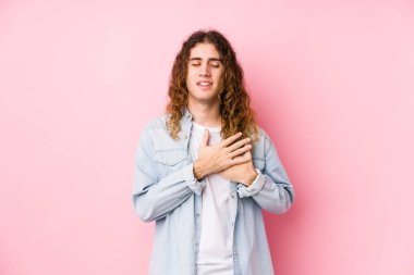 Uzun saçlı adam yalnızmış gibi gülüyor, elleri kalbinde, mutluluk kavramında tutuyor..