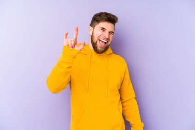 Mor arka planda izole edilmiş genç bir adam boynuzları bir devrim konsepti olarak gösteriyor..