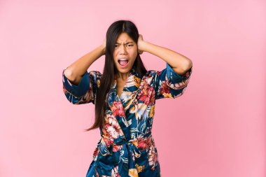 Kimono pijama giyen genç Asyalı kadın kulaklarını elleriyle kapatıyor ve çok ses duymamaya çalışıyor..