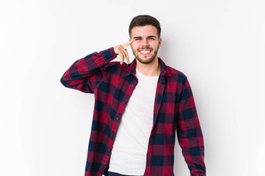 Beyaz arka planda poz veren beyaz tenli genç adam işaret parmağıyla hayal kırıklığı işareti yapıyor..