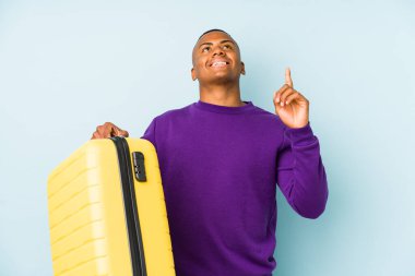 Elinde bavul tutan genç bir gezgin ağzı açık, tepeyi işaret ediyor..