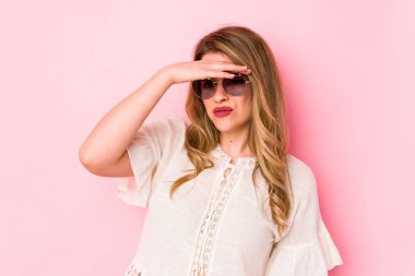 Pembe arka planda gözlüklü genç beyaz kadın tapınaklara dokunuyor ve baş ağrısı çekiyor..