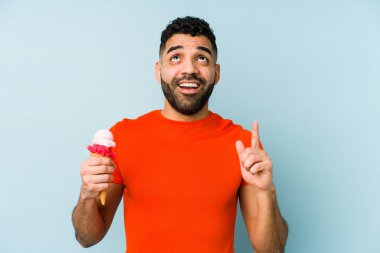 Dondurma tutan genç latin adam ağzı açık bir şekilde yukarı doğru bakıyor..