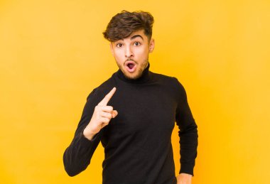 Sarı arka planda izole edilmiş genç bir Arap adamın bir fikri, ilham konsepti var..