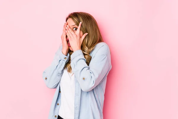 Mujer Joven Caucásica Aislada Sobre Fondo Rosa Parpadea Través Los — Foto de Stock