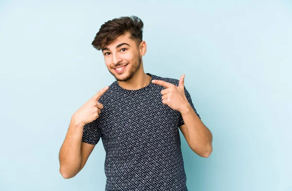 Jonge Arabische Man Geïsoleerd Een Blauwe Achtergrond Glimlacht Wijzende Vingers — Stockfoto