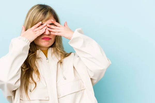 Young blonde caucasian woman afraid covering eyes with hands.