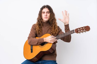 Gitar çalan beyaz bir adam yalnız, beş numarayı parmaklarıyla gülümsüyor..