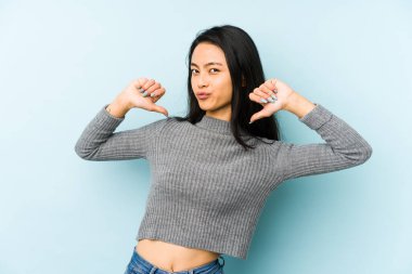 Mavi arka planda izole edilmiş genç Çinli kadın gururlu ve kendinden emin hissediyor, örnek olarak.