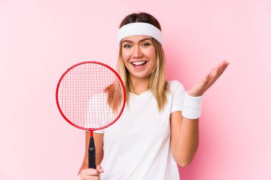 Badminton oynayan genç bir kadın yalnız başına hoş bir sürpriz bekliyor, heyecanlı ve el kaldırıyor..