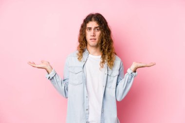 Uzun saçlı adam yalnız poz veriyor. Kafası karışık ve omuz silkiyor. Kopya alanını tutmak için..