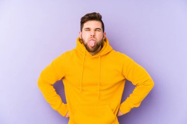 Mor arka planda izole edilmiş genç bir adam komik ve dost canlısı bir dil uzatıyor..