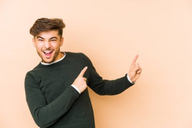 Bej bir arka planda izole edilmiş genç bir Arap adam işaret parmağıyla fotokopi alanını işaret ederek heyecan ve arzuyu ifade ediyor..