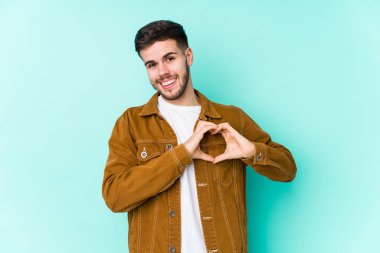 Genç yakışıklı adam gülümsüyor ve elleriyle kalp şeklini gösteriyor..