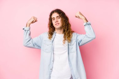 Uzun saçlı adam yalnız poz veriyor. Güçlü bir jest yapıyor. Kadınsı gücün sembolü.