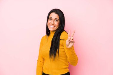 Pembe arka planda soyutlanmış beyaz bir kadın neşeli ve kaygısız parmaklarıyla barış sembolü gösteriyor..