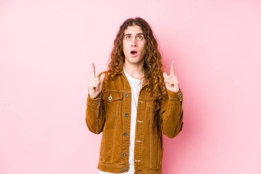 Genç, uzun saçlı adam yalnız poz veriyor. Ağzı açık, yukarı bakıyor..