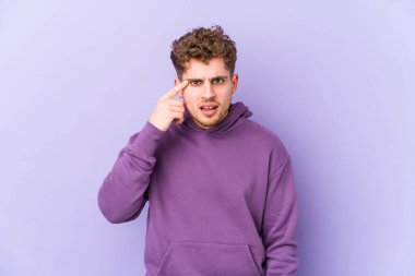 Sarışın, kıvırcık saçlı, beyaz tenli, izole bir adam işaret parmağıyla hayal kırıklığı işareti yapıyor..