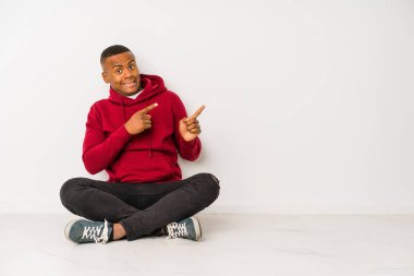 Yerde tek başına oturan genç latin adam işaret parmağıyla fotokopi alanını işaret ederek şok oldu..