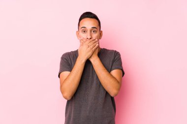 Pembe arka planda poz veren yog latin adam elleri ile ağzı örtüyor..