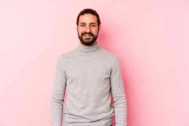 Genç uzun saçlı adam pembe bir arka planda izole edilmiş mutlu, güler yüzlü ve neşeli..