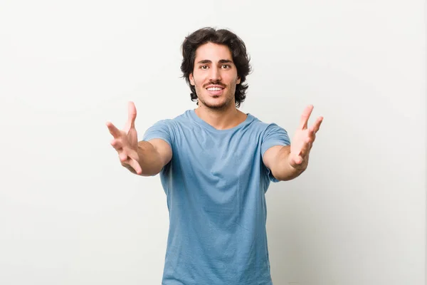 Young handsome man against a white background feels confident giving a hug to the camera.