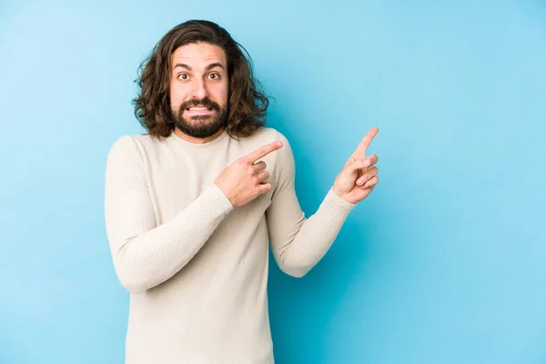 Jonge Lange Haar Man Geïsoleerd Een Blauwe Achtergrond Geschokt Wijzend — Stockfoto