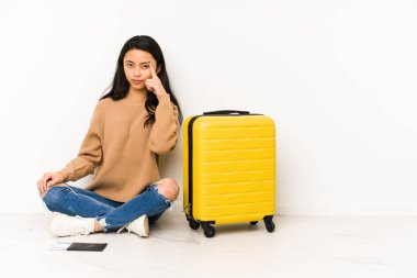 Genç Çinli gezgin kadın, elinde bir bavulla yerde oturuyor. Tapınağı işaret ediyor, düşünüyor ve bir göreve odaklanıyor..