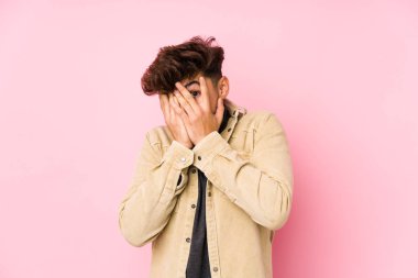 Arka planda poz veren genç bir Arap, korkmuş ve gergin parmaklarıyla göz kırpıyor..