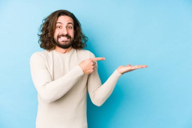 Uzun saçlı genç adam mavi bir arka planda izole edilmiş. Elinde bir fotokopi odası olduğu için heyecanlı..