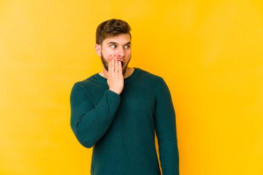 Sarı arka planda izole edilmiş genç beyaz adam gördüğü bir şey yüzünden şoka uğruyor..