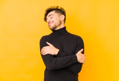 Sarı arka planda yaşayan genç bir Arap adam. Kucaklaşır, kaygısız gülümser ve mutlu olur..