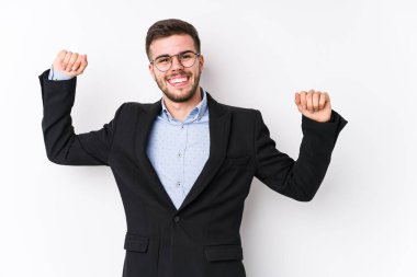 Beyaz arka planda poz veren Kafkasyalı genç bir iş adamı özel bir günü kutlayan Kafkasyalı genç bir iş adamı atlıyor ve enerji ile kollarını kaldırıyor..