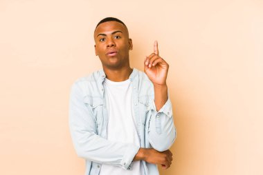 Genç latin adam bej arka planda izole edilmiş. Harika bir fikri var, yaratıcılık kavramı..