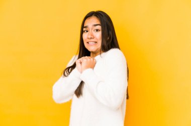 Sarı arka planda yalnız yaşayan genç bir kadın korkmuş ve korkmuş..