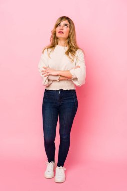 Pembe arka planda duran genç sarışın beyaz kadın tekrarlanan bir görevden yoruldu..