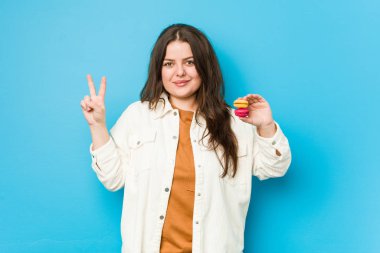 İki numaralı kurabiyeyi parmaklarıyla gösteren kıvrımlı bir kadın..