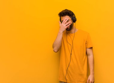 Genç adam müzik dinlerken aynı anda hem utanır hem de güler.