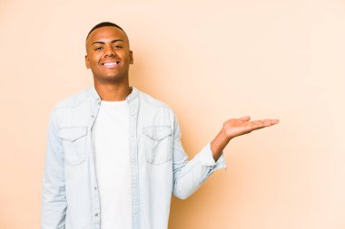 Bej arka planda izole edilmiş genç latin adam bir avuç içinde fotokopi alanı ve belinde bir el daha gösteriyor..