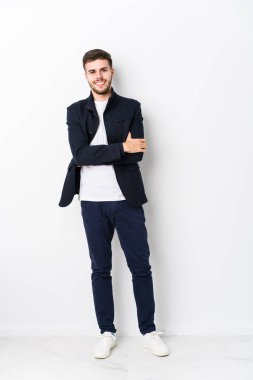 Kendini güvende hisseden, kararlılıkla kollarını kavuşturan genç, beyaz bir adam..