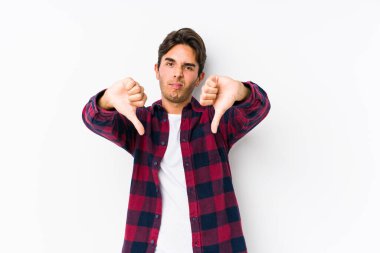 Pembe arka planda poz veren genç beyaz bir adam, izole edilmiş, baş parmağını aşağı gösteren ve hoşlanmadığını ifade eden..