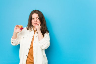 Kurabiye tutan genç kadın rahatlamış fotokopi odasına bakan bir şey düşünüyor..