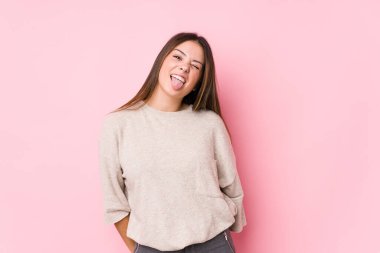 Kafkasyalı genç bir kadın yalnız poz veriyor. Komik ve dost canlısı bir dil uzatıyor..