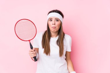 Badminton oynayan beyaz bir kadın omuz silkiyor ve gözleri açık..