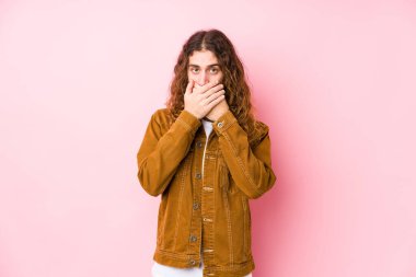 Genç, uzun saçlı, yalnız poz veren, ağzı elleriyle örten, şok olmuş bir adam..