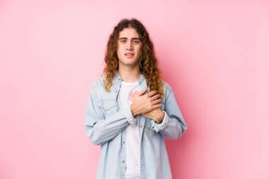 Yalnız poz veren uzun saçlı adam, avuçlarını göğsüne bastıran dostça bir ifadeye sahiptir. Aşk konsepti.