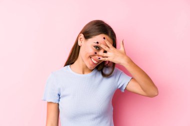 Kayak kıyafeti giyen genç beyaz kadın kameraya parmaklarıyla göz kırpıyor, yüzünü kapatmaktan utanıyor..